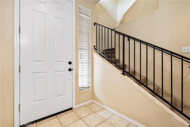 foyer with tile patterned flooring, stairway, and baseboards