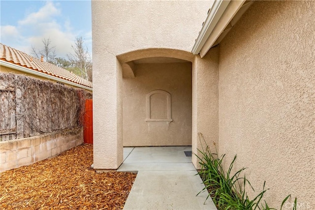 doorway to property with stucco siding and fence