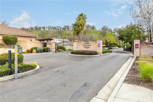 view of road with street lights, a gate, curbs, and a gated entry