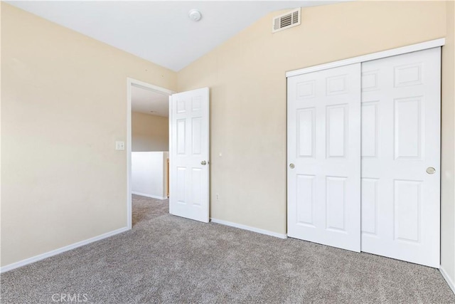 unfurnished bedroom with visible vents, baseboards, carpet, vaulted ceiling, and a closet