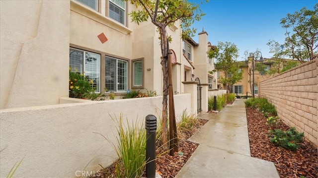 view of property exterior featuring a residential view, a fenced front yard, and stucco siding