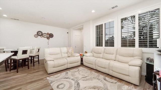 living room with recessed lighting, visible vents, and light wood finished floors