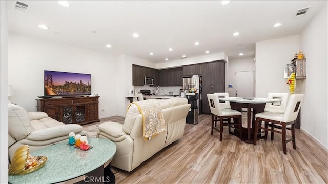 living room with light wood-type flooring, visible vents, and recessed lighting