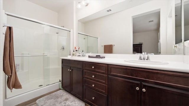 full bath with a shower stall, double vanity, and a sink