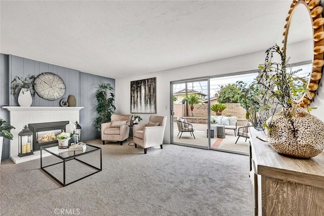 living room featuring a glass covered fireplace, carpet flooring, and a textured ceiling