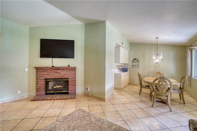 dining space with visible vents, a brick fireplace, a chandelier, light tile patterned flooring, and a textured ceiling