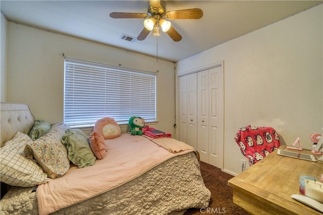 bedroom with dark colored carpet, visible vents, a closet, and ceiling fan