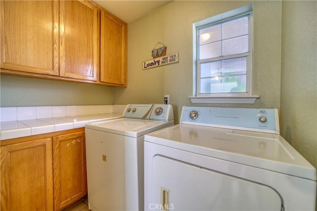 laundry room with cabinet space, a textured wall, and separate washer and dryer