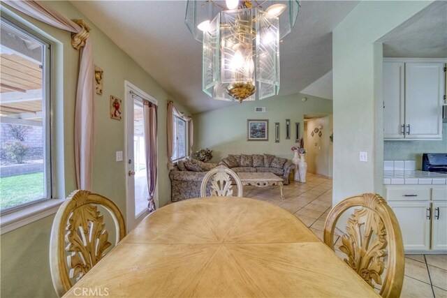 dining area featuring light tile patterned floors, visible vents, a chandelier, and vaulted ceiling