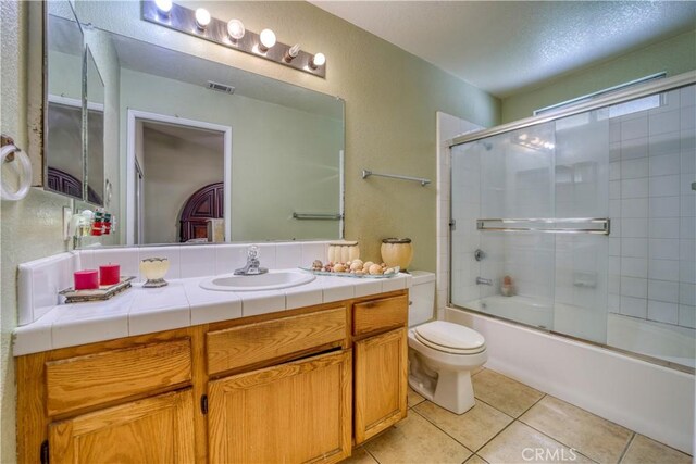 bathroom with vanity, visible vents, enclosed tub / shower combo, tile patterned floors, and toilet