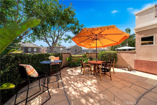 view of patio with outdoor dining space, fence, and a residential view