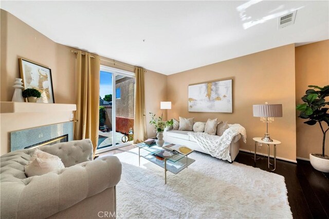 living room with wood finished floors, a fireplace, visible vents, and baseboards