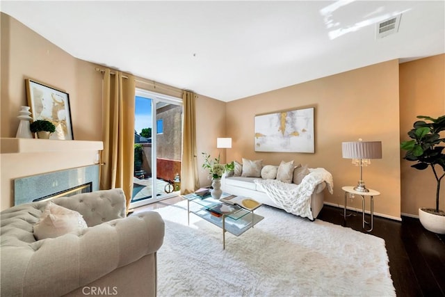 living room featuring wood finished floors, baseboards, and a high end fireplace