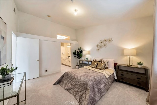bedroom with light carpet and connected bathroom