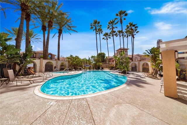 community pool with a patio and fence