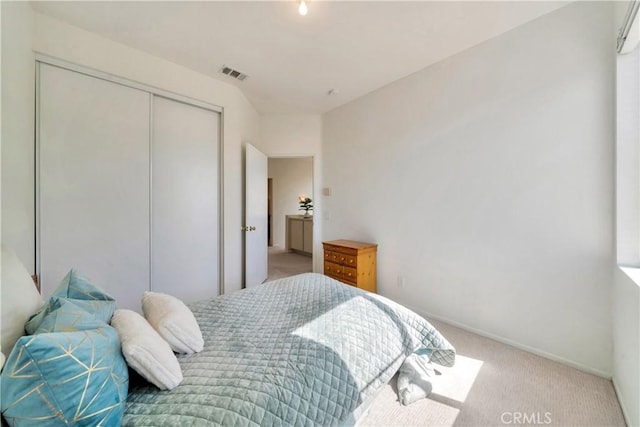 carpeted bedroom with a closet, baseboards, and a wall mounted AC