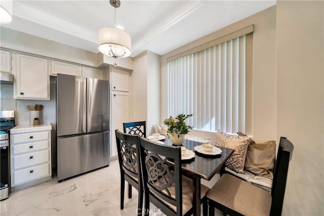 dining room featuring light marble finish flooring and a tray ceiling