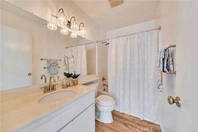 bathroom with toilet, wood finished floors, a notable chandelier, shower / bath combination with curtain, and vanity