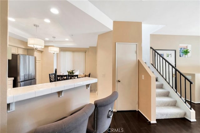 kitchen featuring dark wood finished floors, freestanding refrigerator, tile countertops, recessed lighting, and hanging light fixtures