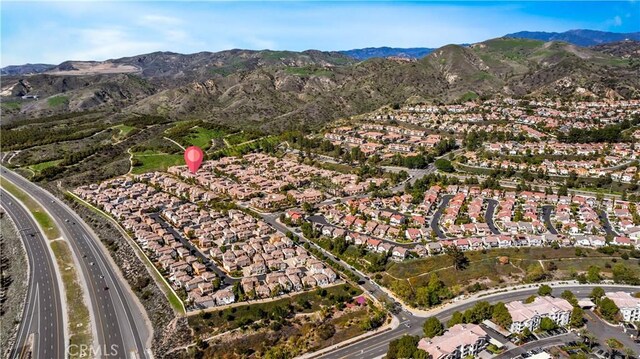 aerial view of property and surrounding area with nearby suburban area, a mountainous background, and a major roadway