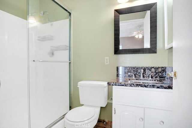 bathroom featuring a shower stall, vanity, toilet, and a ceiling fan