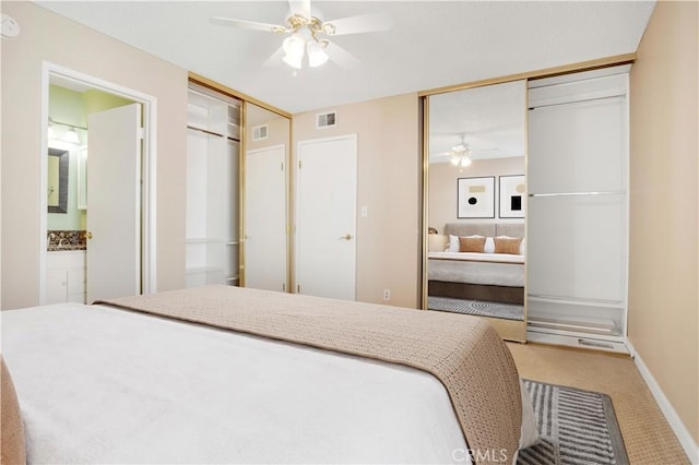 bedroom featuring ceiling fan, visible vents, light carpet, and ensuite bath