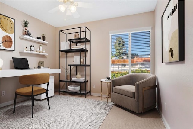 office area with built in study area, a ceiling fan, and baseboards