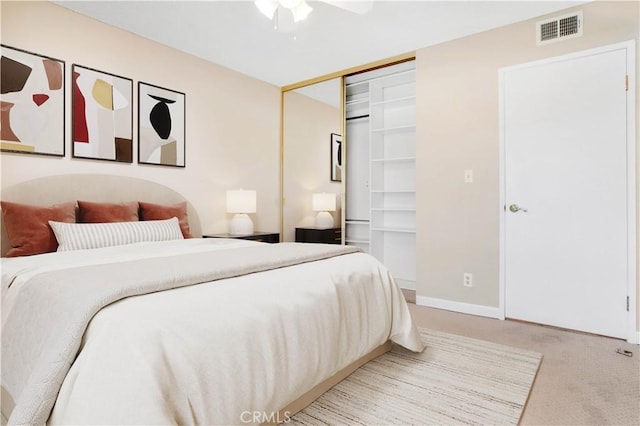 bedroom featuring visible vents, baseboards, ceiling fan, a closet, and light colored carpet