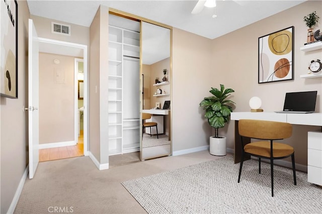 carpeted office space featuring visible vents, baseboards, and a ceiling fan