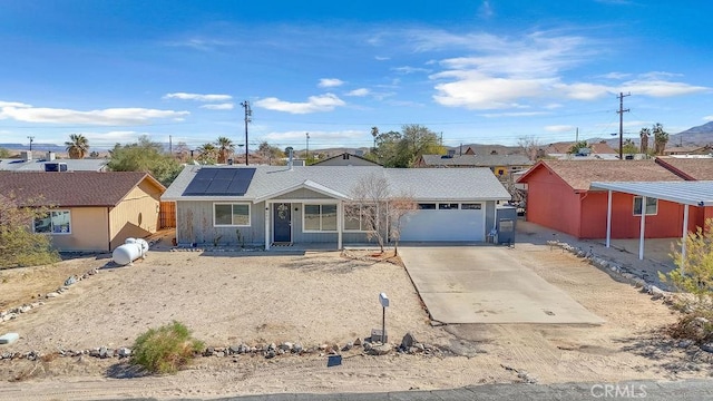 ranch-style house featuring solar panels, driveway, and an attached garage