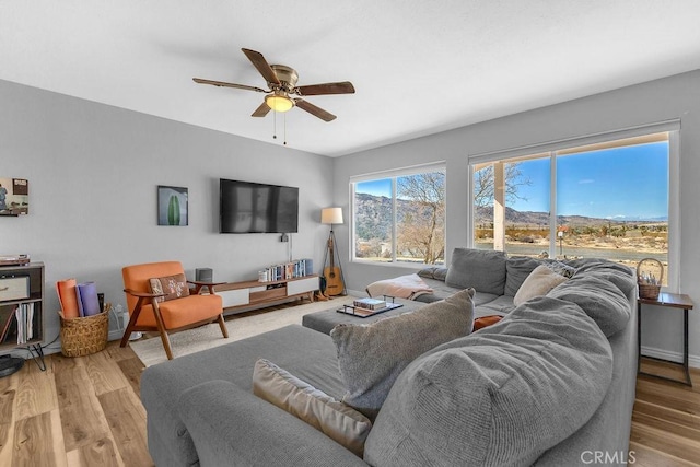 living area with baseboards, a ceiling fan, and wood finished floors