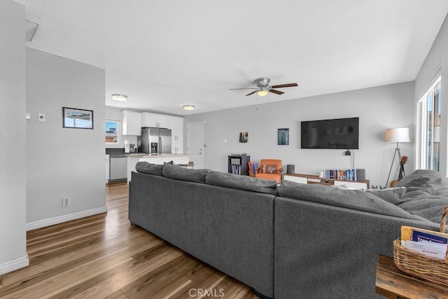 living room with baseboards, wood finished floors, and a ceiling fan