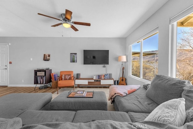 living room featuring baseboards, wood finished floors, and a ceiling fan