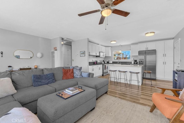 living room with light wood-style floors and ceiling fan