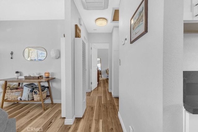 hallway featuring light wood-type flooring and baseboards