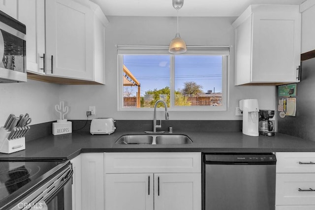 kitchen with a sink, dark countertops, white cabinets, and stainless steel appliances