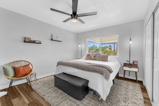 bedroom with a ceiling fan, wood finished floors, baseboards, and a closet