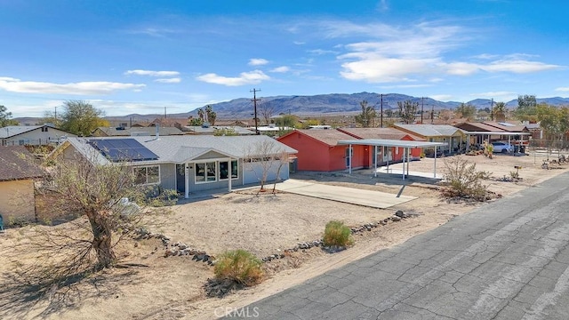 back of house featuring solar panels, an attached garage, a mountain view, and driveway