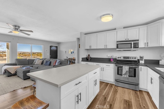 kitchen with white cabinets, light wood-style floors, open floor plan, and stainless steel appliances