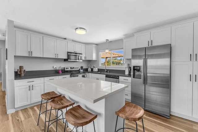 kitchen featuring a breakfast bar area, light wood-type flooring, white cabinets, and stainless steel appliances