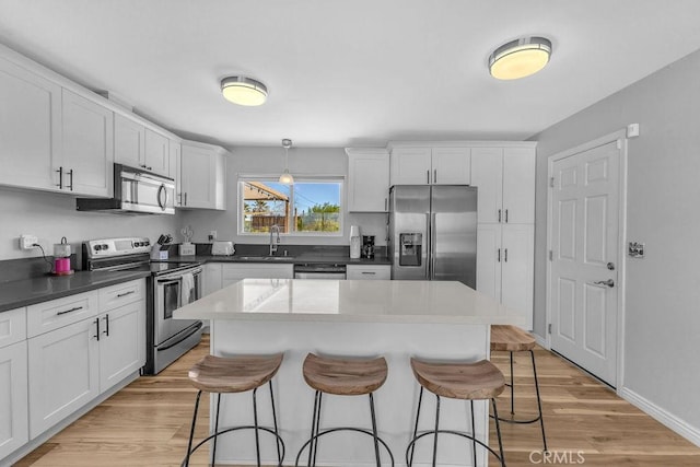 kitchen with a kitchen breakfast bar, light wood-type flooring, appliances with stainless steel finishes, and a sink