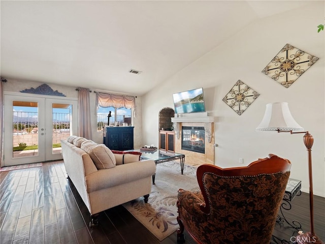 living area featuring lofted ceiling, wood finished floors, visible vents, and a high end fireplace