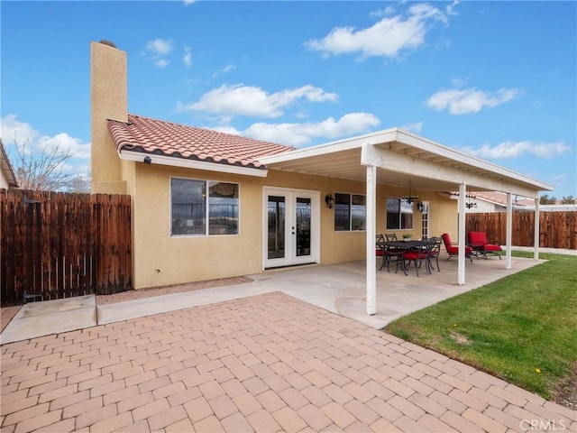 back of property featuring fence, a chimney, stucco siding, french doors, and a patio area