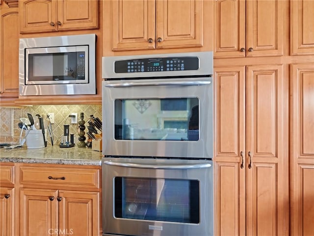 kitchen featuring decorative backsplash, light stone countertops, and appliances with stainless steel finishes