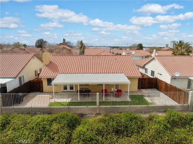 back of house featuring a residential view, a tiled roof, stucco siding, a fenced backyard, and a patio