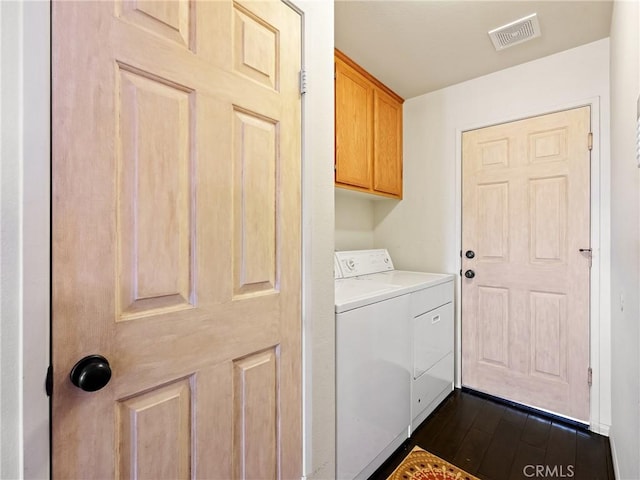 washroom with visible vents, cabinet space, washer / dryer, and dark wood finished floors