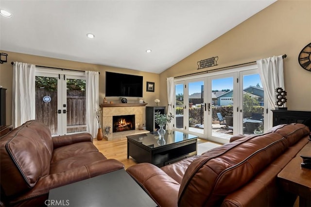 living room with a premium fireplace, vaulted ceiling, recessed lighting, french doors, and wood finished floors