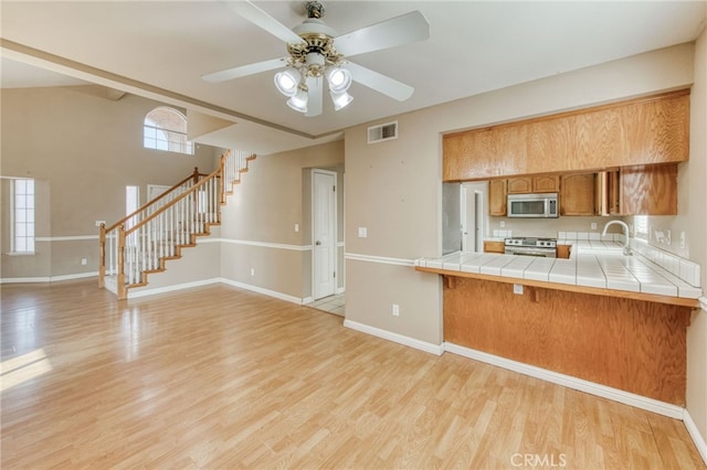 kitchen with visible vents, tile countertops, stainless steel appliances, and light wood-style flooring