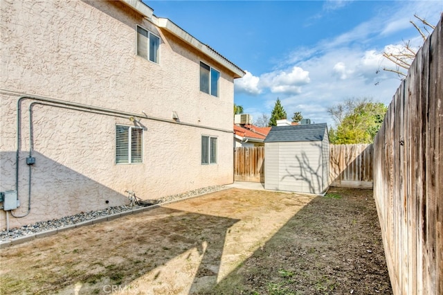 exterior space featuring a storage unit, stucco siding, an outdoor structure, and a fenced backyard