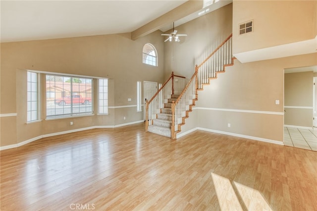 unfurnished living room featuring baseboards, visible vents, high vaulted ceiling, stairs, and light wood-type flooring